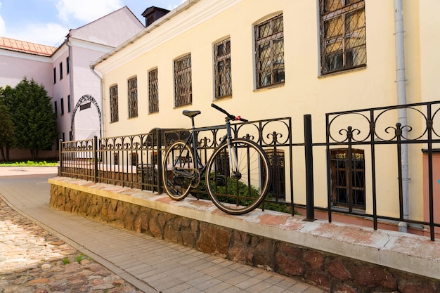 The bike is parked in the city to the fence.