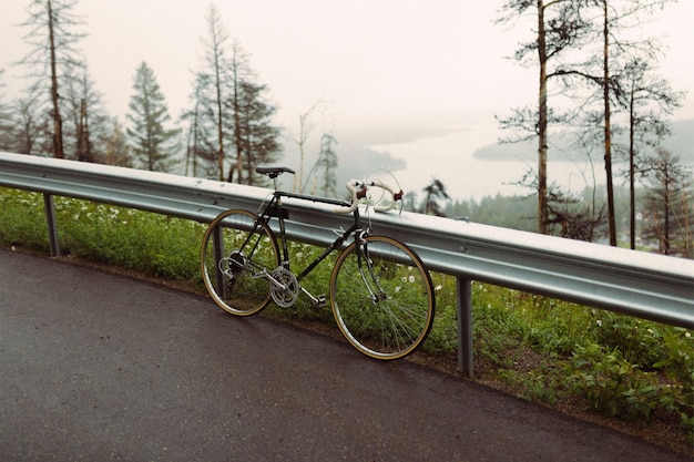 Foto una bicicletta è parcheggiata sul ciglio della strada da un guardrail
