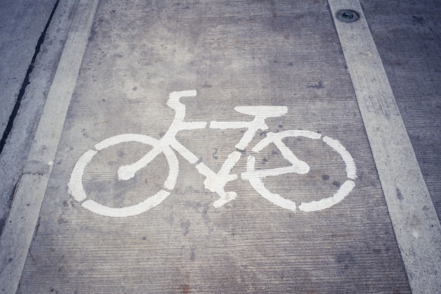 Bike Lane Symbol, белый знак велосипеда на бетонной дороге.