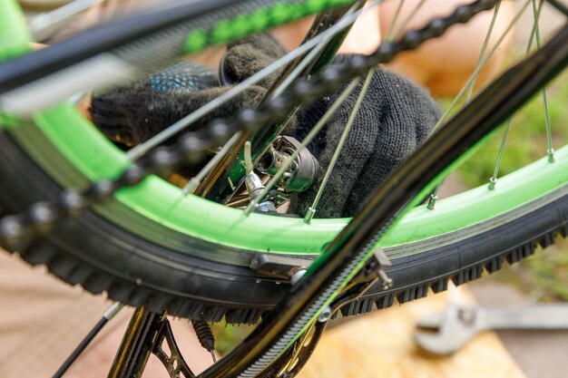 Bike mechanic man repairs bicycle in bicycle repair shop, outdoor. Hand of cyclist bicyclist examines, fixes modern cycle transmission system. Bike maintenance, sport shop concept.