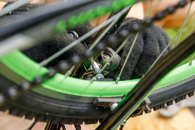 自転車整備士が屋外の自転車修理店で自転車を修理します。サイクリストの手自転車は、現代のサイクルトランスミッションシステムを調べ、修正します。自転車のメンテナンス、スポーツショップのコンセプト。