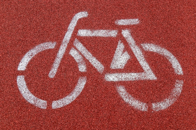 A bike path sign is painted on a rubber track in a park