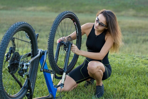 Bike repair Young girl repairing mountain bike on the green hills