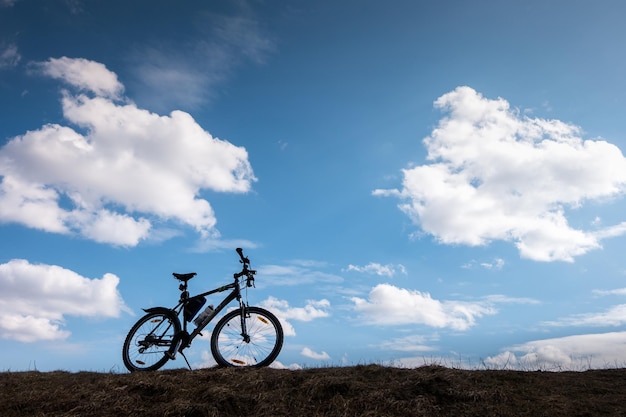 Bike silhouette in blue sky with clouds symbol of independence\
and freedom