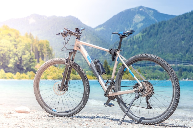 The bike stands against the backdrop of mountains and a lake