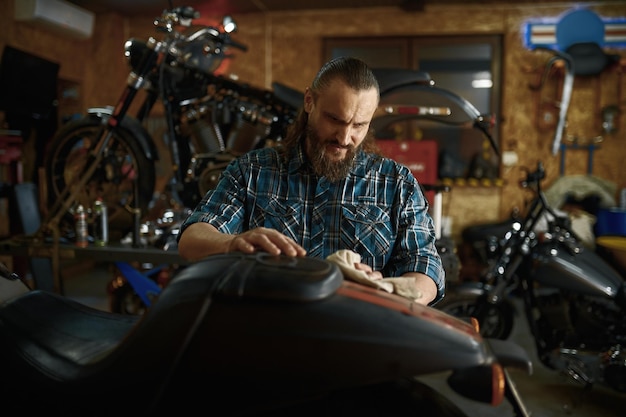 Photo biker cleaning his motorbike in repair shop on weekend