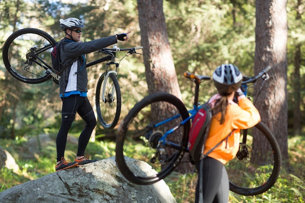 Biker couple holding their mountain bike and pointing at distance