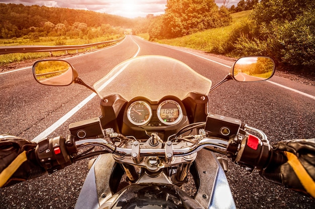 Biker driving a motorcycle rides along the asphalt road. First-person view.