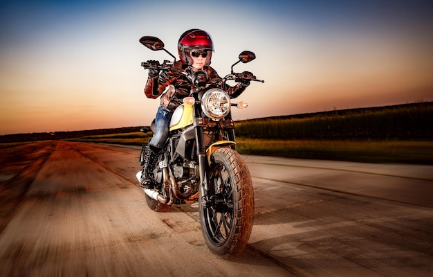 Biker girl in a leather jacket and helmet on a motorcycle