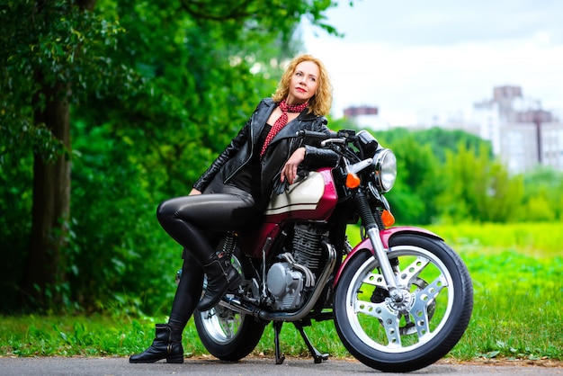 Biker girl in a leather jacket on a motorcycle