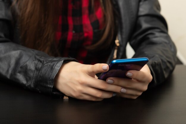 Ragazza del motociclista in giacca di pelle con il telefono