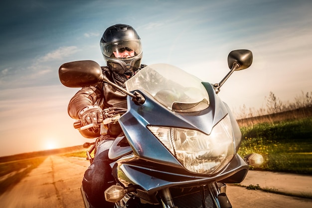 Biker in helmet and leather jacket racing on the road