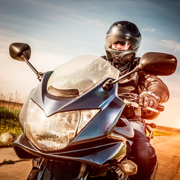 Biker in helmet and leather jacket racing on the road