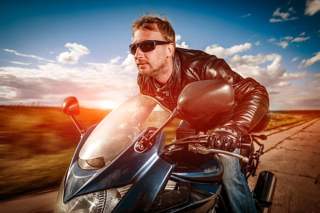 Biker in helmet and leather jacket racing on the road