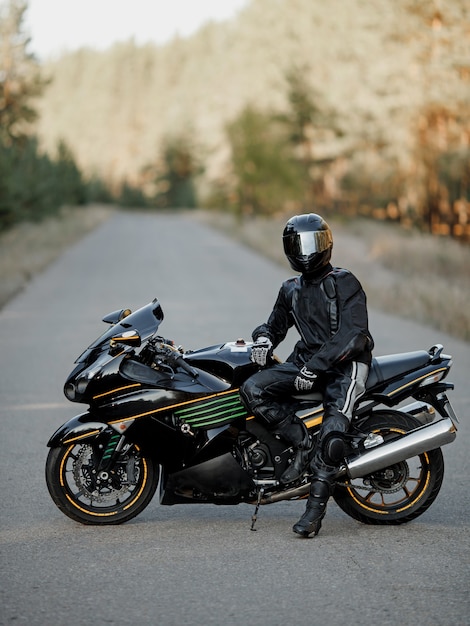 Foto biker in un casco e dispositivi di protezione in pelle si siede su una motocicletta, una motocicletta sportiva veloce