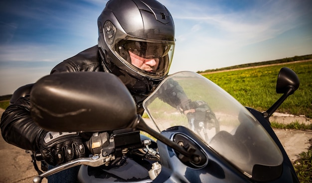 Biker in helm en leren jas racen op de weg