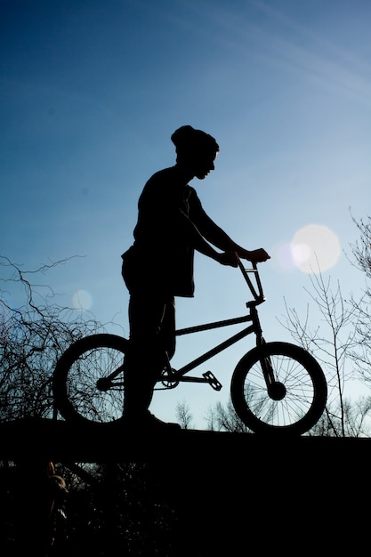 Biker is standing with a bicycle on a background of dark sky. Sport lifestyle.