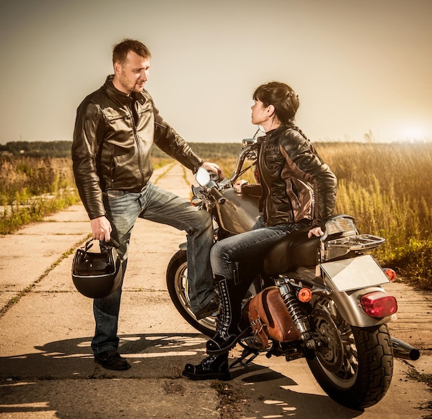 Biker man and girl sits on a bike