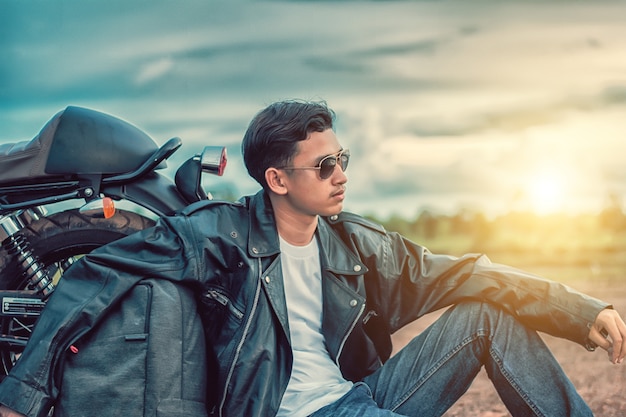 Biker man sitting with his motorbike beside the natural lake and beautiful.