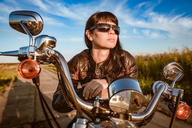 Biker meisje in een leren jas en zonnebril zittend op de motorfiets