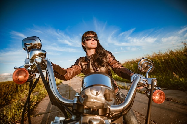 Biker meisje in een leren jas en zonnebril zittend op de motorfiets