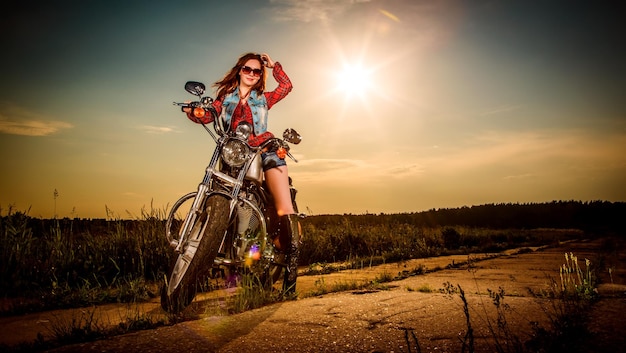 Biker meisje met zonnebril zittend op motorfiets