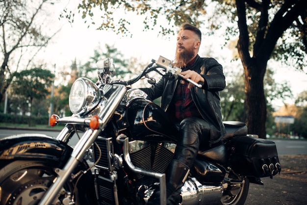 Biker sitting on a motorcycle leaning on a helmet