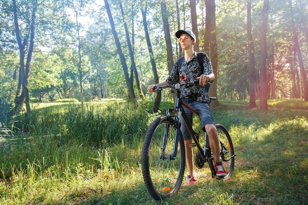 Biker stopped in a city park against the backdrop of the setting sun