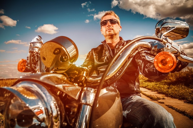 Motociclista in occhiali da sole e giacca di pelle su una moto