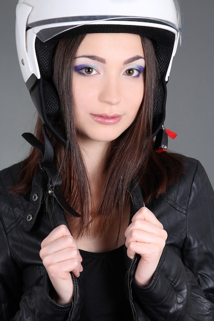 Biker woman in helmet on head over grey