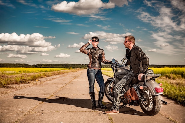 Bikers couple Man and woman near a motorcycle on the road