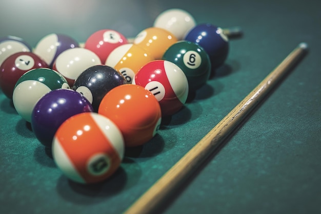 Biljartkeu en een piramide van kleurrijke ballen op een groene pooltafel