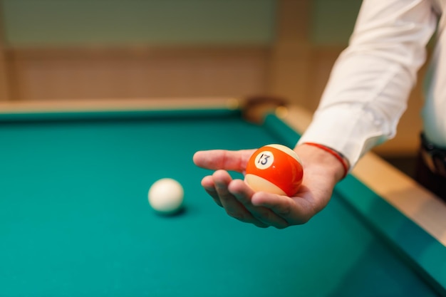 Biljartspeler houdt bal in zijn handpalm aan biljarttafel of snooker Amerikaans biljart pool sportspel