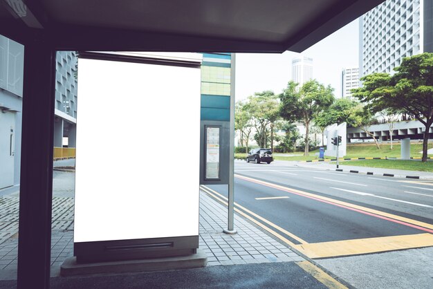 billboard op bushalte met lege reclamebanner op zonovergoten straat.