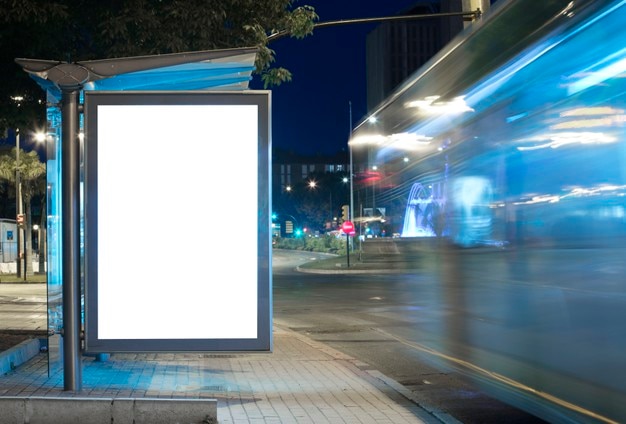 Foto tabellone per le affissioni con luce nel centro della città di notte con autobus in movimento