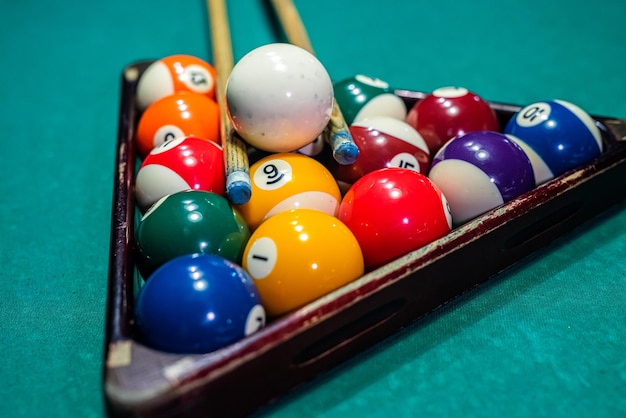 Billiard balls on the pool table with player\'s hands and\
stick