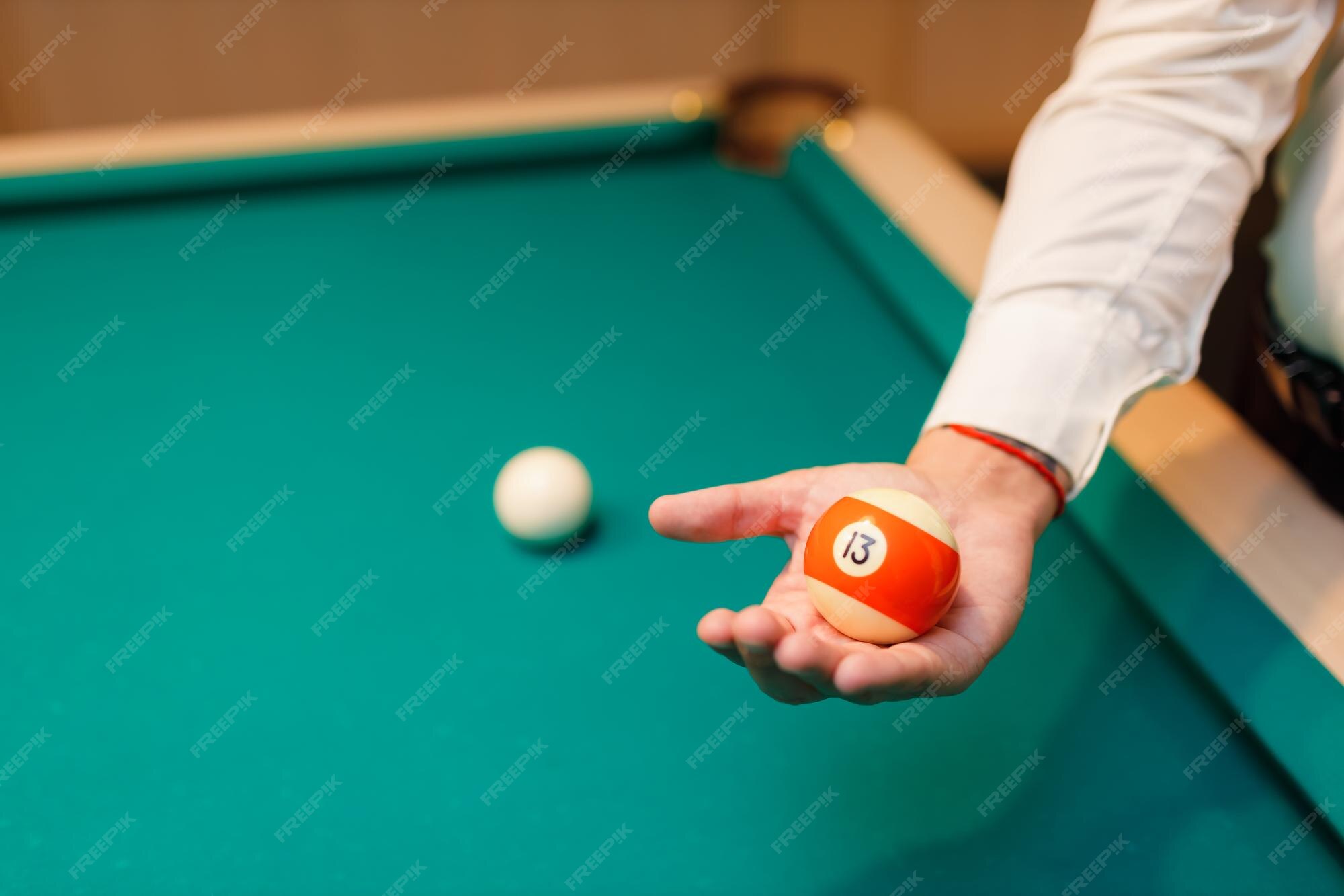 Premium Photo Billiard player holds ball in his hand palm at billard