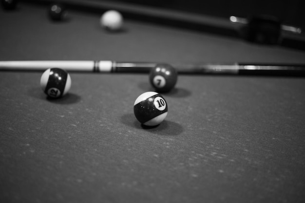 Photo billiard table in the billiard room with balls and cue black and white photo