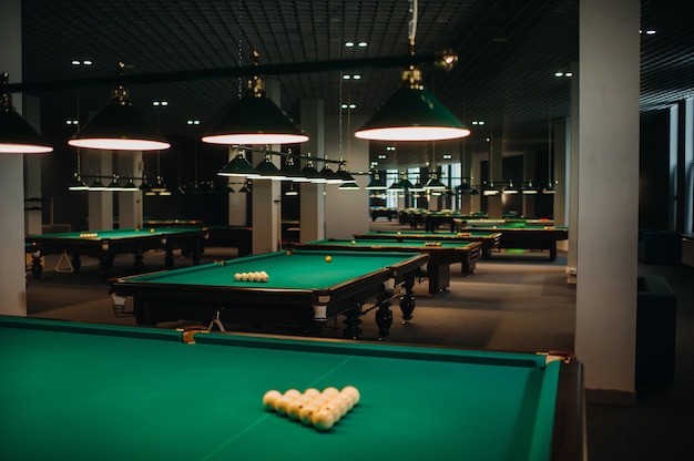 Billiard table with green surface and balls in the billiard club.