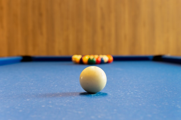 Billiards pool game. White ball on spot with set colours ball in background on blue table.