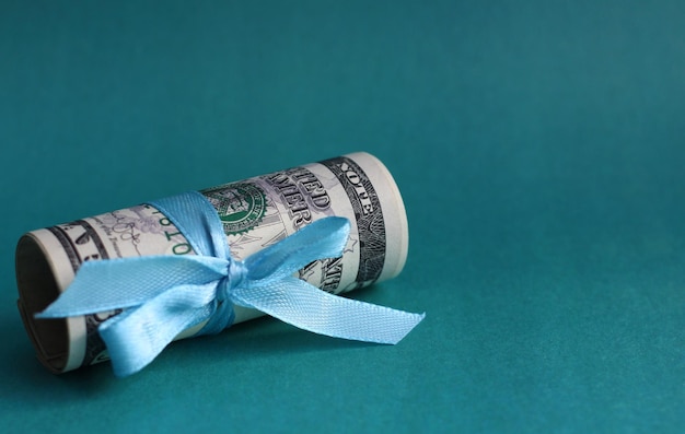 Bills of dollars in a roll with a satin ribbon as a gift