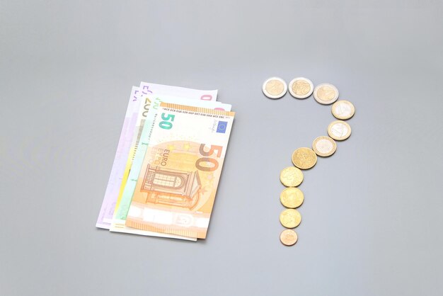 Bills euro banknotes and a question mark from coins on a gray background World financial crisis