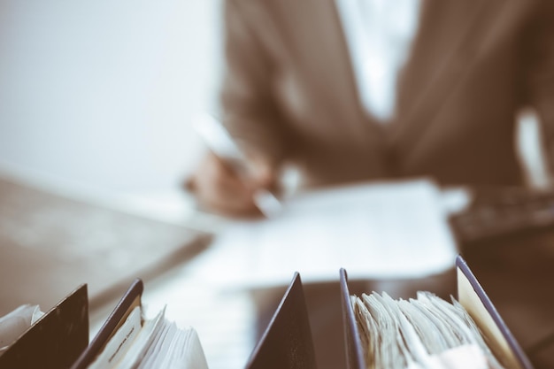 Binders of papers waiting to process by bookkeeper woman or financial inspector, close-up. Business portrait. Audit or tax concepts.