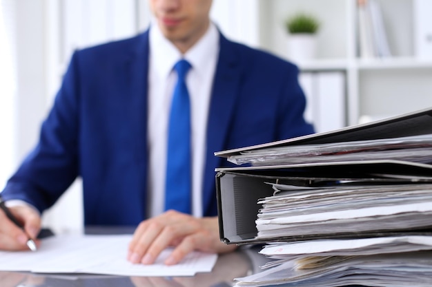 Photo binders with papers are waiting to be processed with businessman back in blur accounting planning budget audit insurance and business concept