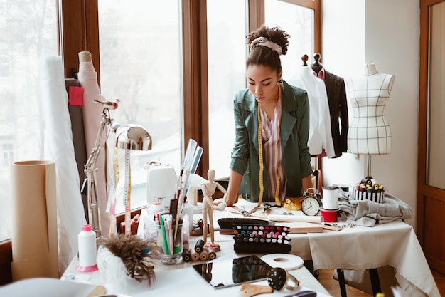 Binnen werkproces vrouw ontwerper staande met meetlint om haar nek