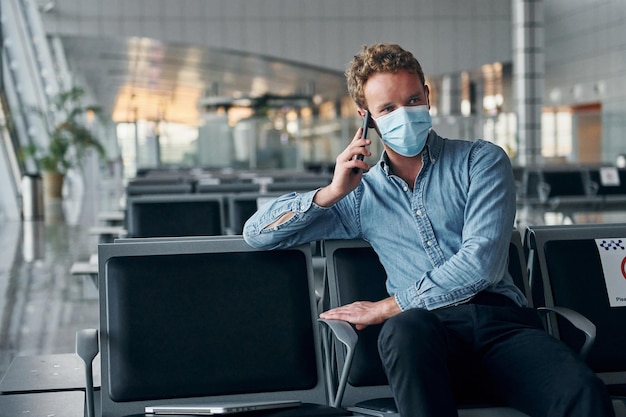 Binnen zitten Jonge man in formele kleding is in moderne luchthaven Conceptie van vakantie