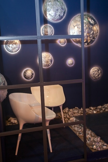 Foto binnenaanzicht van witte creatieve stoelen bij de muur met glanzende decoratieve planeten