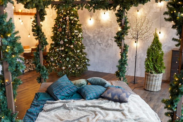 Binnenland en vakantieconcept - comfortabele slaapkamer met bed en kerstmisslingerlichten thuis