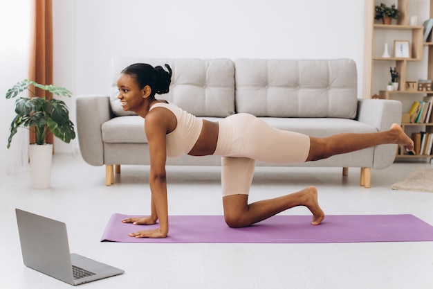 Binnenlandse training. Jonge sportieve zwarte vrouw doet plank oefening thuis, opleiding in de woonkamer