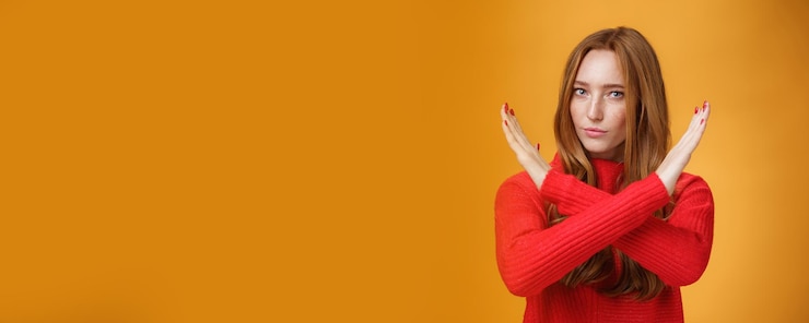 Foto binnenopname van een zelfverzekerde, aantrekkelijke krachtige vrouw met rood haar en sproeten, gekruiste armen in geen en